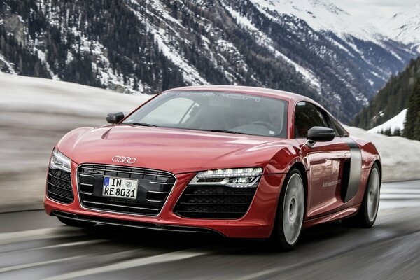 Coche rojo Audi r8 en el fondo de las montañas nevadas