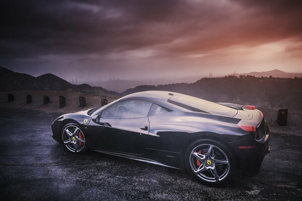 Ferrari negro de perfil en el fondo de las montañas