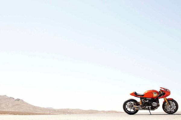 Orange Motorrad auf dem Hintergrund des Himmels und der Berge