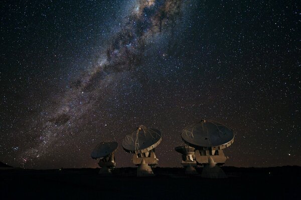 Quatre radiotélescopes sur fond de galaxie