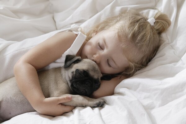 Cute girl sleeping in an embrace with a pug