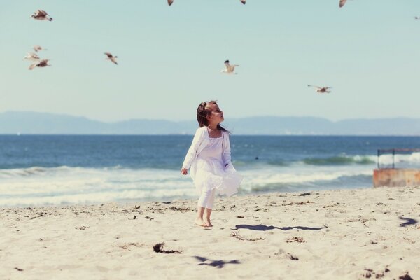 A little girl runs along the beach