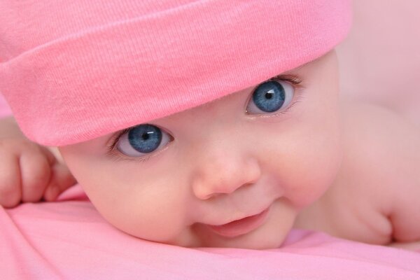 Bambino con gli occhi azzurri in un cappello rosa