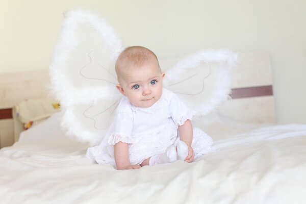 Bébé ange sur un lit blanc