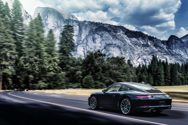 Une voiture de sport est représentée à l arrière, sur fond de montagnes et d arbres