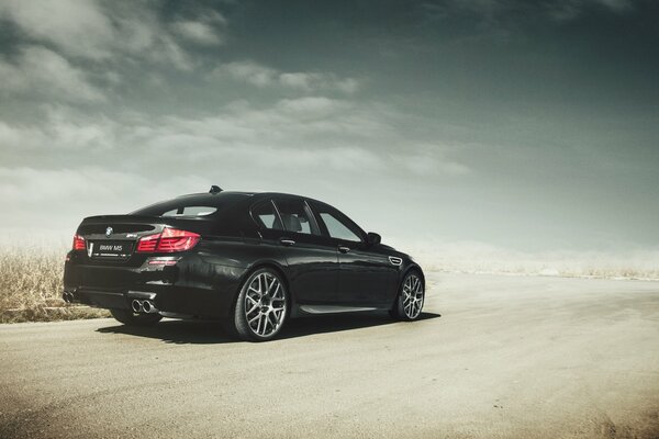 Black BMW M5 on a sandy road