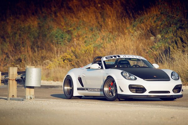 A beautiful, white car is driving along the road
