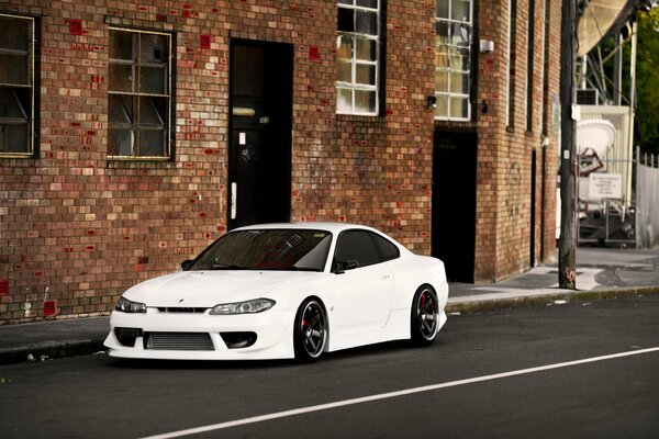White Nissan near a brick wall