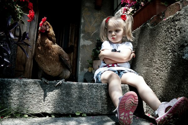 Ein Mädchen mit weißen Haaren sitzt auf der Treppe neben einem Huhn