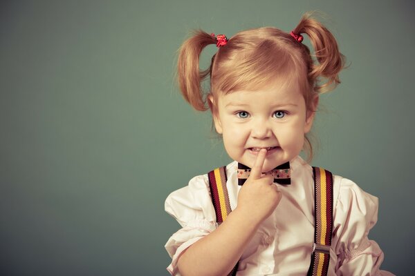 A little girl with two ponytails in suspenders