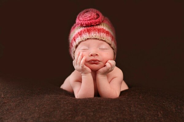 Piccolo bambino addormentato su sfondo marrone cashmere
