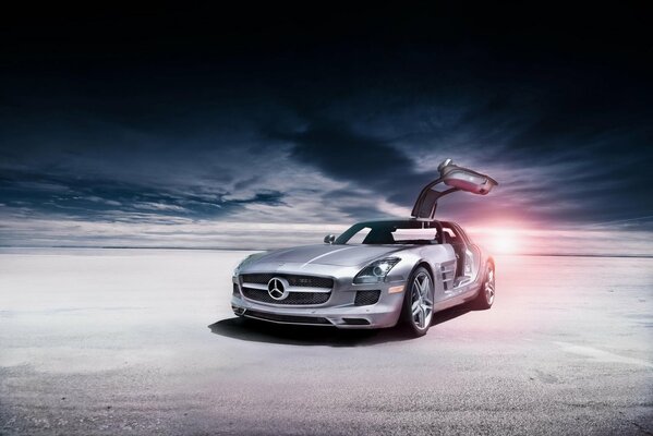 Un Mercedes plateado se detuvo en el desierto. La belleza de las nubes que corren en el fondo y el sol que se va es fascinante
