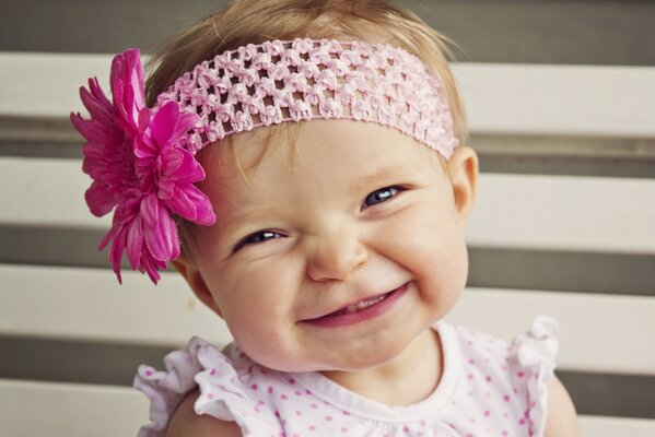 Bambina in una fascia con un fiore sorridente