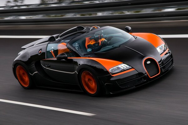 Une voiture de course noire et orange roule sur l asphalte