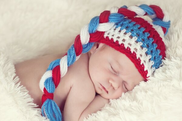 Bambino che dorme in un cappello su un plaid