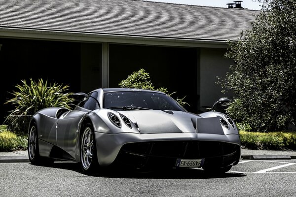 Silver handsome pagani huayra on the background of a private residential building