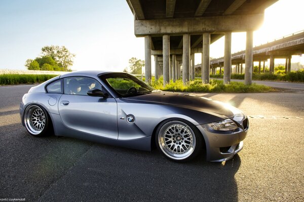 Szary samochód marki BMW pod betonowym mostem