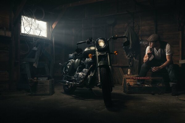 Мужчина в гараже с мотоциклом Royal Enfield