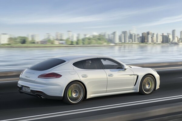 White Porsche Panamero rides on asphalt against the background of the city