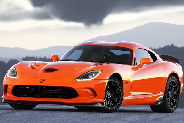 Sur un fond noir et blanc se trouve une voiture orange