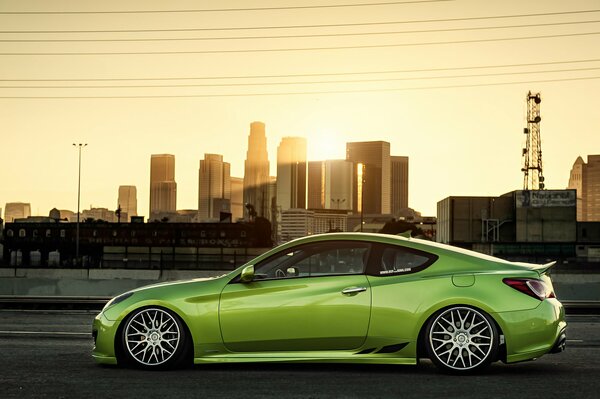 Light green sports car on the background of the city at sunset