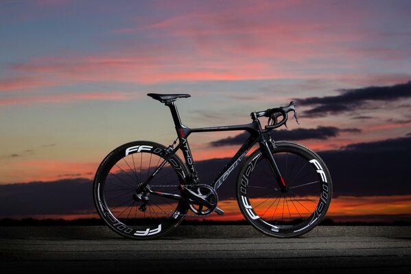 Bicicleta de carbono negro en el fondo de la puesta de sol