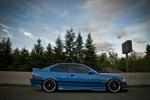 Bleu tuning BMW E36 sur fond de forêt