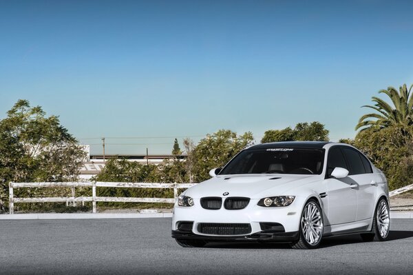 Белый bmw м3 e90 на фоне деревьев
