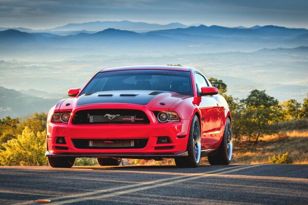 La Ford Mustang rossa guida lungo la strada