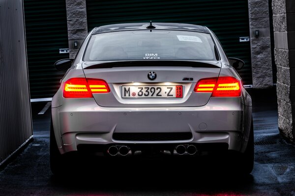 Une BMW blanche avec des phares rouges se tient dans la rue