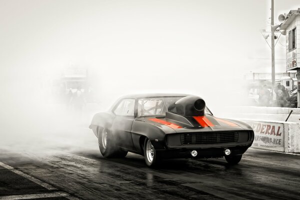 Black Chevrolet with red stripes on a foggy road