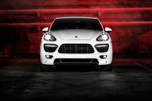 Белый Porsche Cayenne в темноте с красной подсветкой на фоне не труб