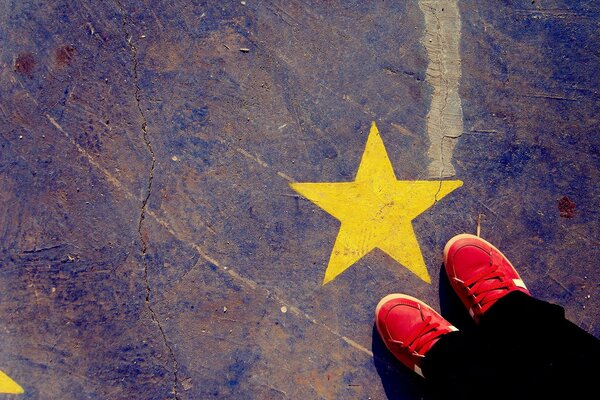 Una estrella amarilla está pintada, y un hombre con Zapatillas rojas está cerca