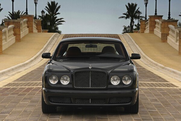 Black Bentley on a cobblestone road, front view