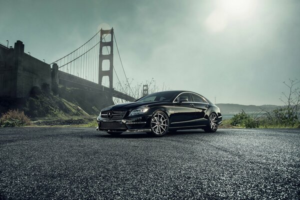 A black Mercedes-Benz is standing near the bridge