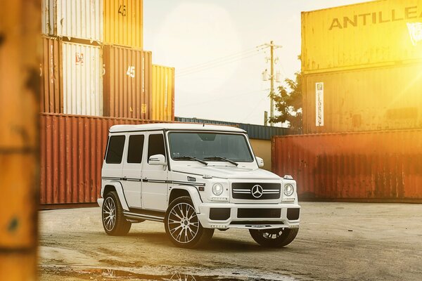 Mercedes stands among metal containers