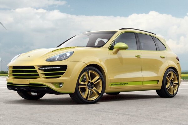 Porsche золотистого цвета на фоне ветряных мельниц и облаков