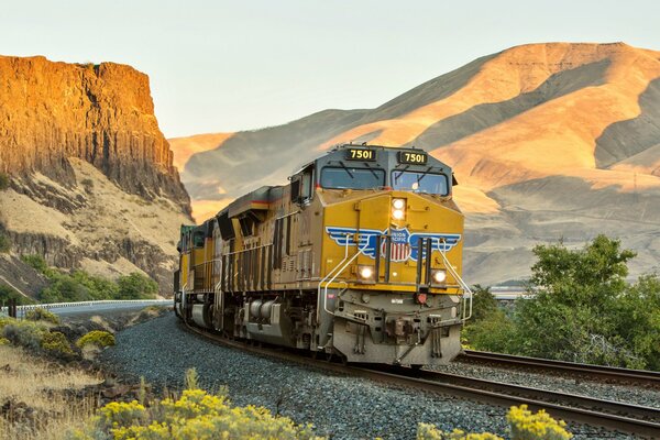The locomotive moves along the rails among the majestic mountains