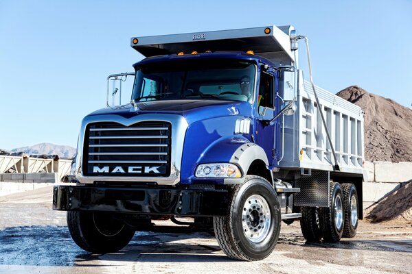 Heavy dump truck on the background of a mountain of sand
