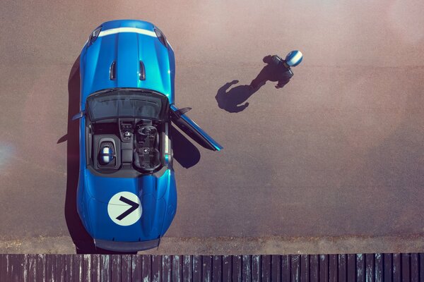 Auto sportiva blu con porta aperta. L autista con il casco blu è uscito dall auto sportiva blu senza chiudere la porta. Vista dall alto di un giaguaro blu con una striscia bianca