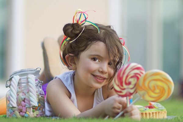 A cheerful girl with lollipops and a jar of sweets