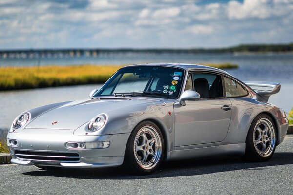 A silver Porsche is driving on the highway