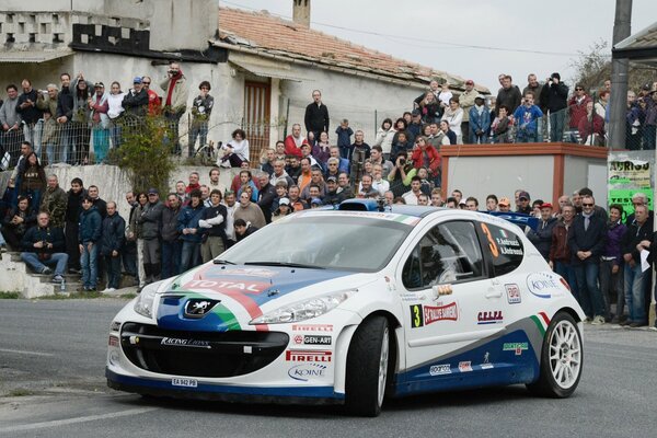 Lindo Peugeot blanco y azul rodeado de espectadores