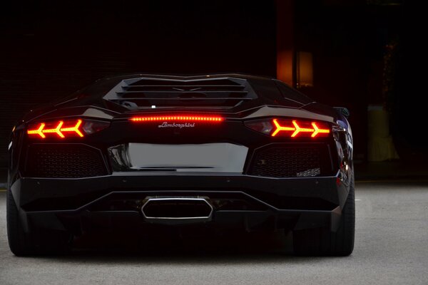 Culo negro Lamborghini con los faros encendidos