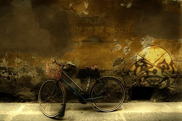 A bicycle with a basket on a wall background and a drawing of a scary clown