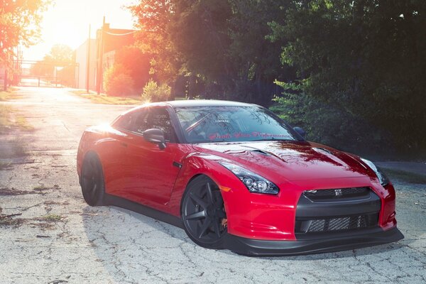 Red sports car coupe on the background of sunset and trees