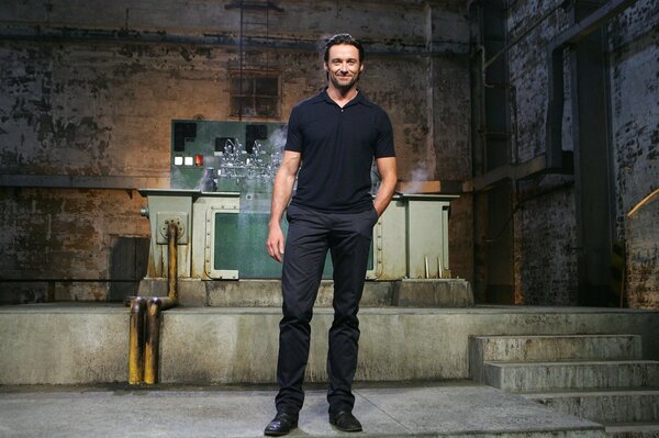 Sonriente Hugh Jackman en el fondo de una habitación abandonada