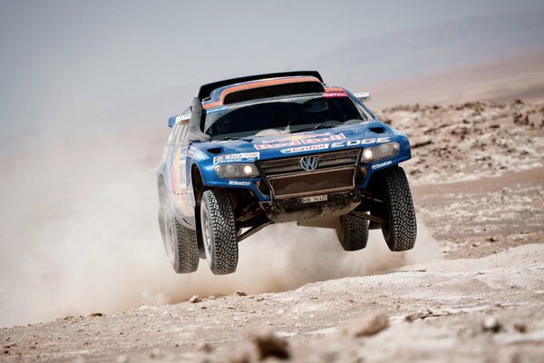 Une voiture de sport volkswagen Dakar volant sur un terrain désertique