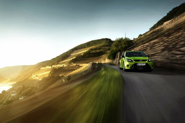 Light green Ford focus in motion at sunset, along the mountains