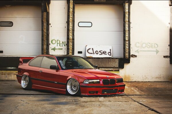 Red tuned BMW e 36 in the parking lot. near the warehouse